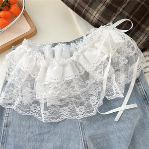 Close-up of white layered floral lace ruffle with satin ties on denim background