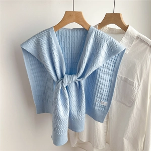 Dettaglio di scialle in maglia azzurro con strisce verticali su una camicia bianca elegante