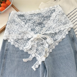 Detail of white lace triangle scarf with floral patterns and bow tie on denim base