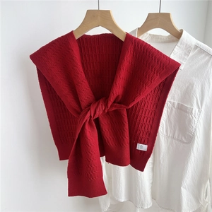 Dettaglio dello scialle in maglia rossa con trecce spesse su camicia bianca