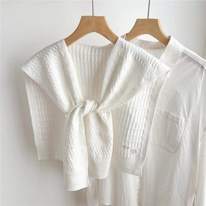 Primo piano dello scialle in maglia beige con trama a nido d'ape su camicia bianca