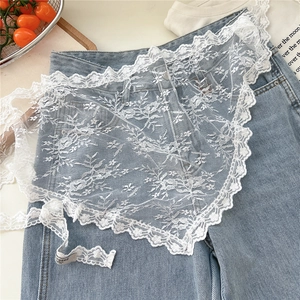 Detailed close-up of white floral lace embroidery on a mesh apron over denim fabric