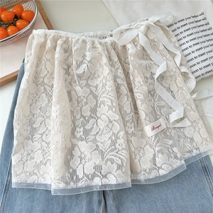 Detail of white floral lace overlay skirt with silk bow tie and delicate crochet texture