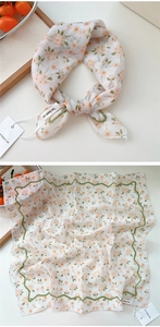 Detail view of cotton-linen floral scarf showing orange prints and green wavy borders