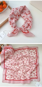 Close-up of a pink floral cotton linen scarf with red flower patterns and brand tag