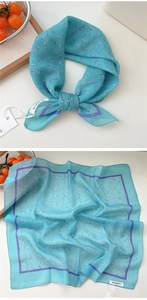 Detail of blue floral square cotton linen scarf with elegant purple trim and brand tag