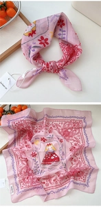Detail of pink cotton linen scarf featuring floral patterns and a cartoon girl illustration