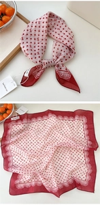 Detailed view of red and white polka dot silk scarf with lace edges and bow pattern