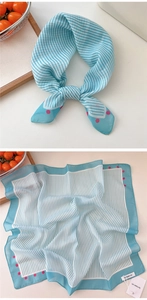 Detail of blue white striped silk scarf with pink polka dots on a wooden tray