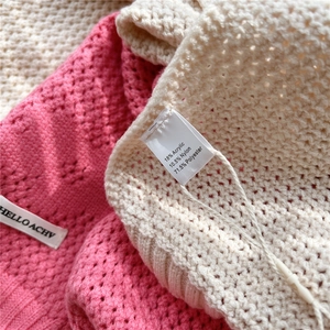 Macro detail of floral knit shawl showing hollow crochet craft and brand material label
