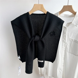 Close-up of black hollow knit shawl with honeycomb crochet texture and brand label