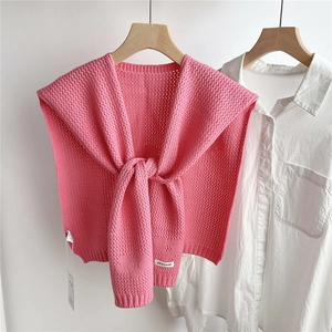 Detail of pink knitted shawl with crochet texture and ribbon tie on white shirt