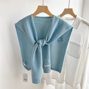 Close-up of light blue hollow knit shawl with floral crochet details and tie design