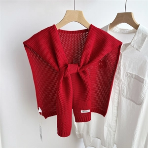 Detail of red hollow-out knitted shawl with decorative knot over a white shirt