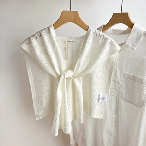 Detail eines weißen Strickschals mit Rautenmuster auf einem Holzbügel