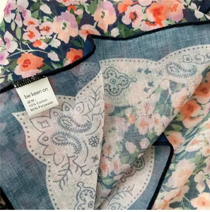 Dettaglio del tessuto di un foulard quadrato con motivo floreale ed etichetta lavaggio