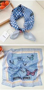 Dettaglio di un foulard in seta a scacchi azzurro con motivi di farfalle rosa