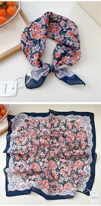 Dettaglio di foulard in seta blu scuro con fiori e bordo paisley in tessuto leggero