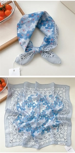 Dettaglio di un foulard in cotone celeste con motivo paisley e drappeggio annodato elegante