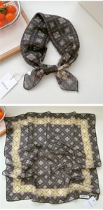 Dettaglio di un foulard quadrato floreale con base nera e bordo verde raffinato