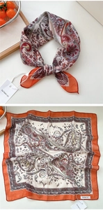 Dettaglio di un foulard quadrato paisley con bordi arancioni su vassoio di legno