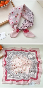 Dettaglio di foulard rosa in cotone e lino con motivi floreali paisley e bordi a zigzag