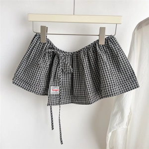 Close-up of black and white plaid mini skirt accessory with waist tie and logo detail