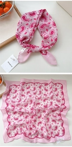 Dettaglio di un foulard quadrato rosa con motivo paisley rosso e trama in tessuto cotone