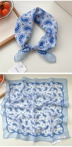 Dettaglio di un foulard quadrato paisley azzurro con trama in cotone e lino e nodo