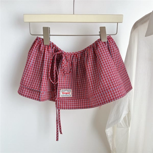 Detail of red and white plaid skirt accessory with drawstring and woven brand label