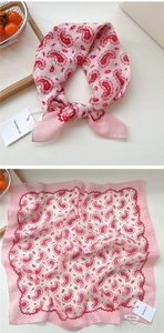 Dettaglio di un foulard quadrato rosa con motivo paisley e bordo in pizzo rosso ondulato