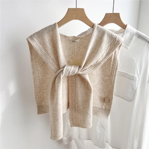 Detail of chunky cable knit 100% wool beige shawl draped over a white shirt with tie knot
