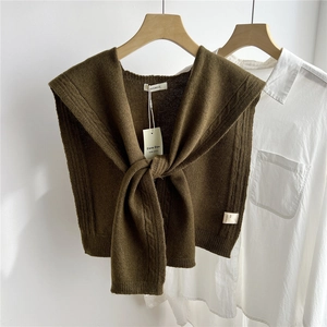 Close-up of olive green knitted wool shawl featuring thick cable knit texture and lapel