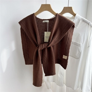 Detail of a brown 100% pure wool knitted shawl with elegant cable knit texture on a hanger