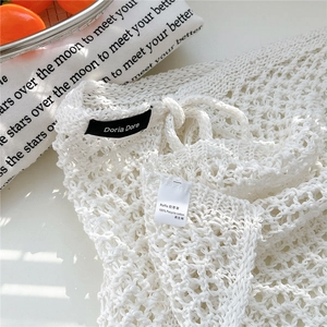 Detail of white hollow crochet bag showing recycled cotton and raffia material labels