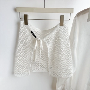 Detail of white crochet knit mini skirt showing intricate hollow pattern and tie-waist cord