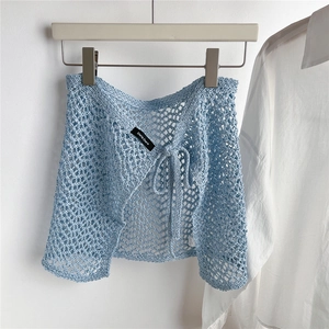 Close-up of light blue hollow crochet mini skirt with lace-up detail and brand label