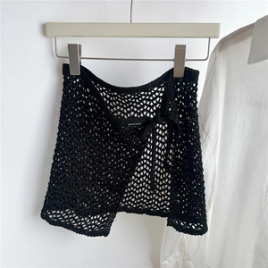 Detailed view of black crochet mesh wrap mini skirt with waist tie and brand label