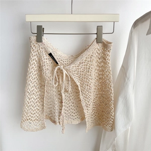 Detail of cream crochet knit mini skirt with open mesh texture and colorful speckles