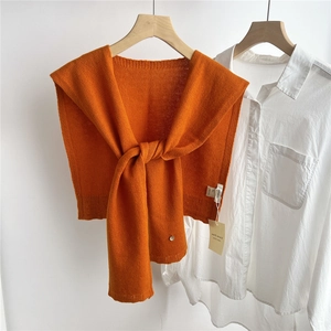 Detail of orange wool knit shawl showing 100% wool texture and delicate button closure