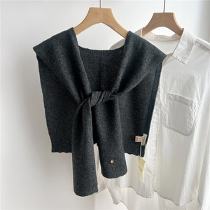 Detail of dark gray wool knit shawl with button, styled over a white shirt