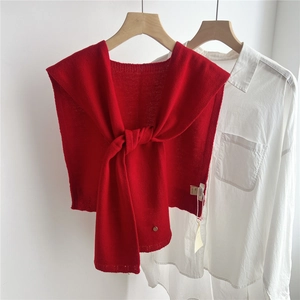 Detail of red wool knit shawl with elegant tie-knot draped on a white shirt