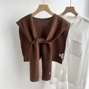 Detail of dark brown wool knitted shawl with premium logo tag and golden metal button