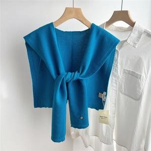 Detail of royal blue wool knitted shawl with metal button on a white shirt