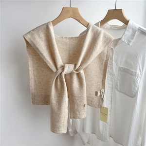 Close-up of lightweight beige 100% wool knitted shawl draped on a hanger with shirt