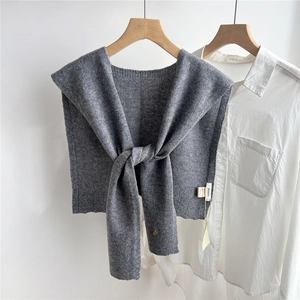 Detail of grey wool knitted shawl with 100% wool label over a white shirt