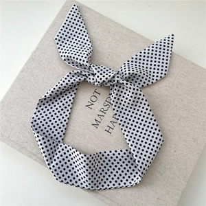 Détail d'un ruban à cheveux à pois blancs et noirs avec un nœud sur tissu gris