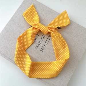 Détail du bandeau à pois jaunes avec nœud papillon sur un fond de livre texturé