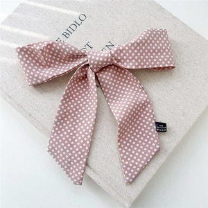 Détail du ruban à cheveux rose à pois en satin avec étiquette sur un livre texturé