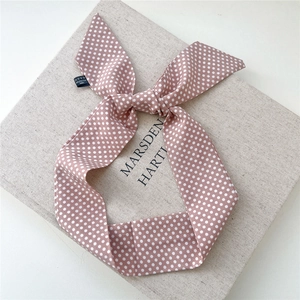 Gros plan d'un foulard en soie à pois roses avec étiquette 100% polyester